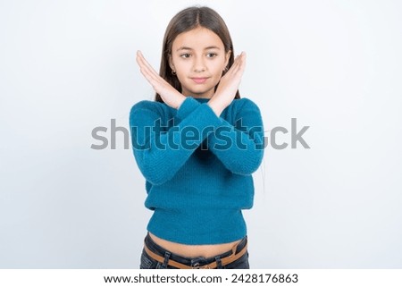 beautiful kid girl wearing blue knitted sweater Rejection expression crossing arms doing negative sign, angry face
