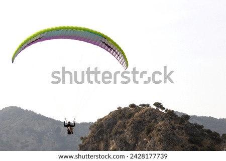 A paraglider in Fethiye Oludeniz. Parachute flies past the hills. Extreme sports idea concept. Feeling of freedom. Adrenaline, adventure. Horizontal photo. Outdoor. Tourist activity.