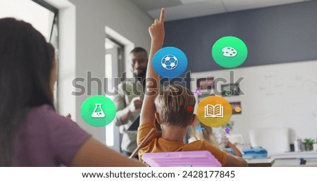 Image of school icons over african american male teacher and pupils raising hands in class. School, education, childhood and learning, digitally generated image.