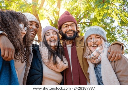 Friends are sharing a happy moment, smiling for a picture in a park. They are wearing hats and standing under a tree, enjoying the fun together. High quality 4k footage