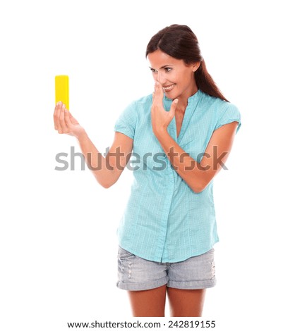 Charming young woman taking photos of herself or selfie using a yellow mobile phone while smiling in white background