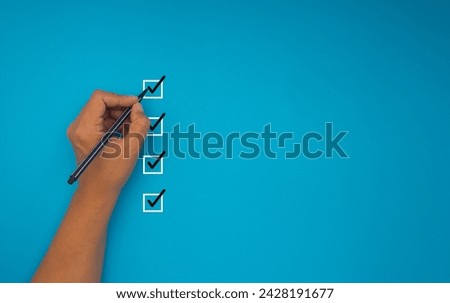 Checklist concept. Close-up of hand holding a pen, mark four correct sign symbols in boxes on a blue background. Space for text. Checklist, Approved concept