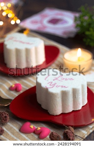 A heart shape ice-cream cake for lovers  wrote in text "I love you forever" in a red color plate with candle light with mini heart elements. Valentines and wedding ambiance