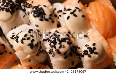 Beautiful close-up photo of sushi with salmon. Delicious Japanese food photo in high quality. Stock photo of sushi. Black sesame and cheese cream.