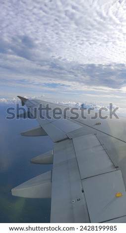 airplane wings and view of blue sky and clouds seen from airplane window