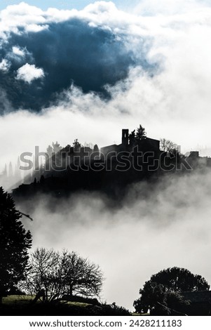 Silhouetted village of montefioralle in early morning mist as sun breaks through, tuscany, italy, europe