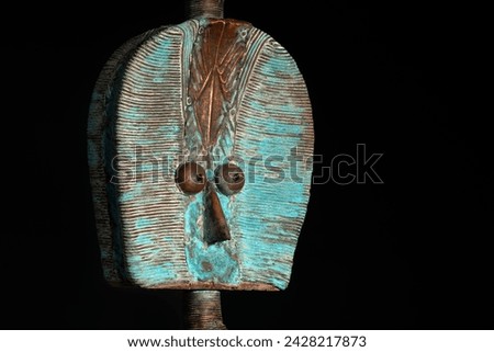 Close up of a wooden Kota reliquary figure from Gabon, isolated on a black background. Tribal African art, showcasing masterful craftsmanship and spiritual symbolism. Royalty-Free Stock Photo #2428217873