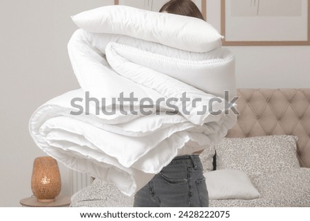 Woman holding pile of soft white folded duvet and pillows at home in her bedroom, cozy domestic lifestyle, housewife cleaning, tidying up bedroom, housework chores concept.	 Royalty-Free Stock Photo #2428222075