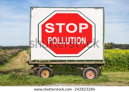 rural scene with a trailer in front of a field. On the trailer is a big red stop sign with the words stop pollution. Concept for environment protection