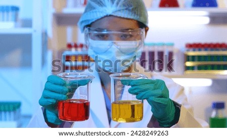 Scientists are doing research in a science lab. A medical chemist in a white coat, gloves and goggles looks at a glass tube. Compare two different liquid samples. and discuss future experiments.