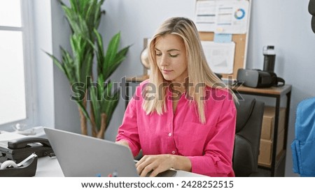 Focused woman working efficiently at her bright office setup with laptop, enhancing the corporate aesthetic.