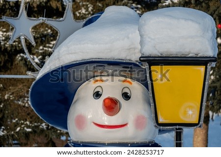 Portrait of a toy snowman in a hat, covered with snow.