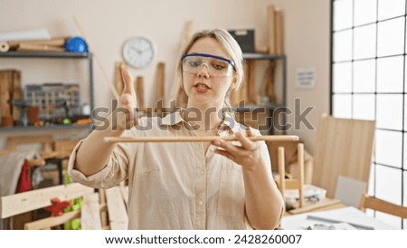 Blonde woman focused on precision in a sunny carpentry workshop wearing safety goggles.