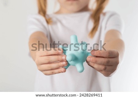 A blonde girl holds a model of a virus in her hands. Concept of ARVI and influenza virus in children, close-up Royalty-Free Stock Photo #2428269411
