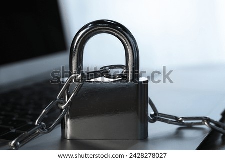 Cyber security. Laptop with padlock and chain on table, closeup