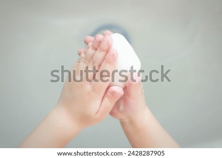 A child washes his hands with soap in the bathroom. The concept of hygiene and clean hands, infection, close-up Royalty-Free Stock Photo #2428287905