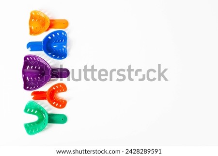Multi-colored dental spoons for taking an impression of the dental jaw on a white background. Orthodontics in dentistry, close-up Royalty-Free Stock Photo #2428289591