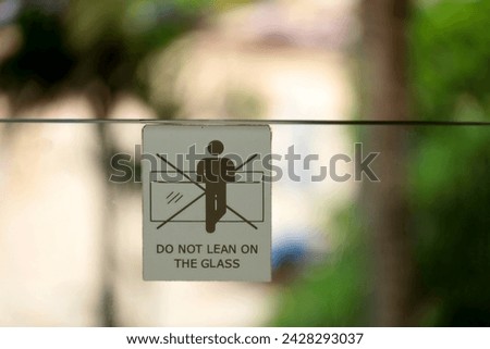 writing prohibiting and advising not to lean on glass on a glass railing on the balcony.