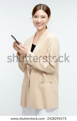 Beautiful Asian business woman holding smartphone on white background.