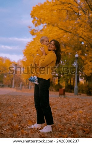 happy family, mother and daughter playing and laughing on autumn walk, falling autumn leaves, family weekend
