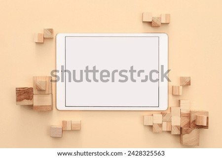 Modern tablet and wooden cubes on beige background, flat lay. Space for text