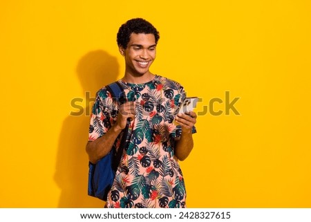 Photo of young happy student international trade program guy using smartphone wearing backpack isolated over yellow color background