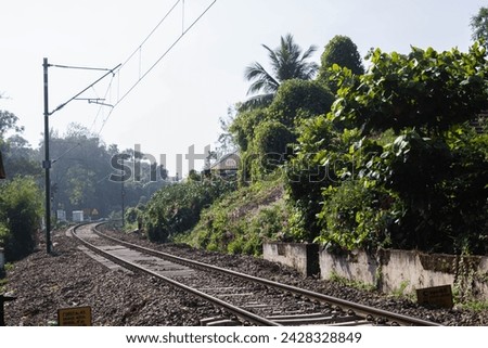 Picture taken from a train crossing of a train track with a train coming in Alleppey  