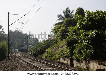 Picture taken from a train crossing of a train track with a train coming in Alleppey  