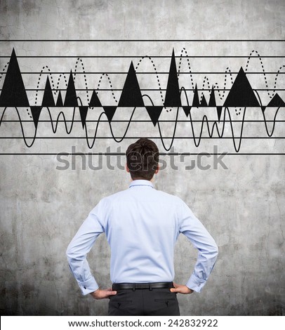 businessman looking to drawing graphs  on wall