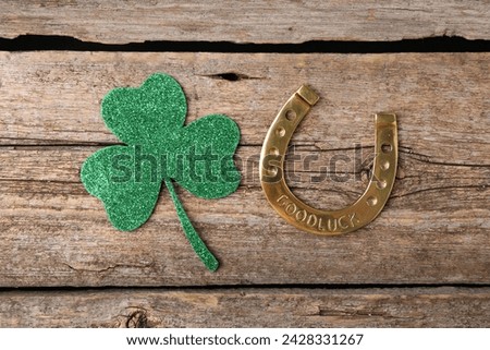 St. Patrick's day. Golden horseshoe and green decorative clover leaf on wooden table, flat lay