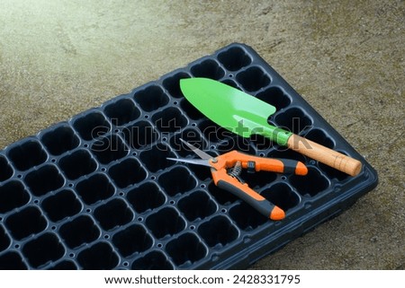 Nursery tray or Seed starter tray for planting with green steel shovel and pruning shears on concrete background for concept of agricultural and nursery equipment. Royalty-Free Stock Photo #2428331795
