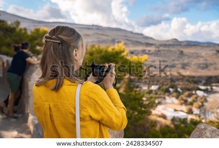 A woman photographer takes pictures of the Lindos beach.