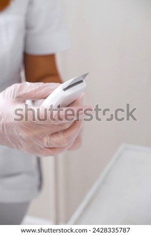 Close-up of beautician's hands in gloves with professional ultrasonic facial cleansing device, ready for skin care. Vertical photo
