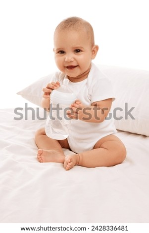 Portrait of beautiful, calm, adorable baby girl, child posing on bed in white clothes against white background. Concept of childhood, family, care, motherhood, infancy, heath Royalty-Free Stock Photo #2428336481