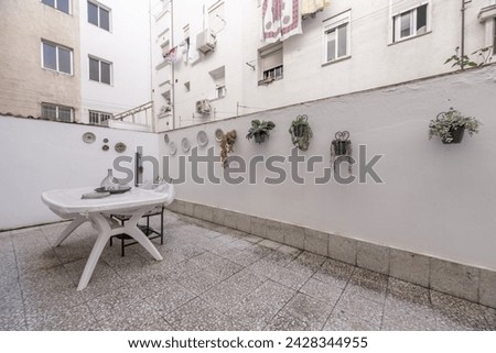 An interior patio of a house with terrazzo floors and white walls with plates hanging on them