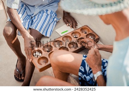 Two men play mancala on Cape Verde Royalty-Free Stock Photo #2428352425