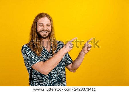 Photo of funky positive guy wear print shirt pointing two fingers empty space isolated yellow color background