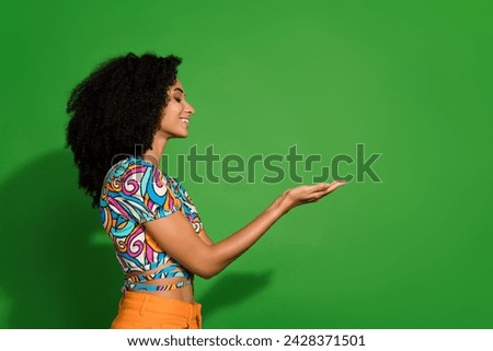 Side profile photo of cheerful cute girl sister curly hair holding arms to show her friends new toy isolated on green color background