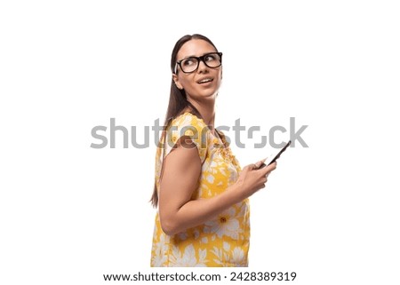 a young woman dressed in a yellow sundress and with glasses chatting on the phone