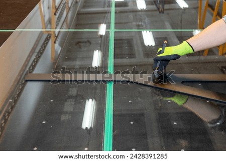 A glazier cuts panes in the factory, cuts thick glass, Professional glazier equipment, Concept, glass for shower cabins, showcases, glass development, close up Royalty-Free Stock Photo #2428391285