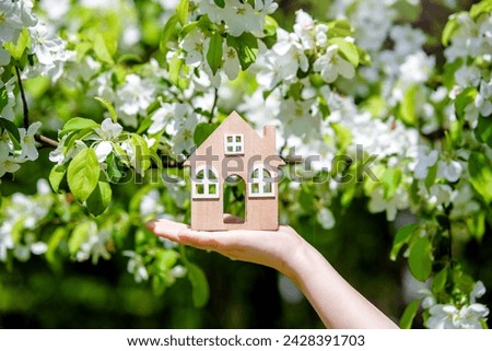 The girl holds the house symbol against the background of blossoming appletree
 Royalty-Free Stock Photo #2428391703