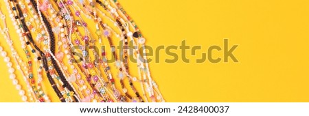 Banner with chains of beads, pearls and natural stones on a yellow background. 