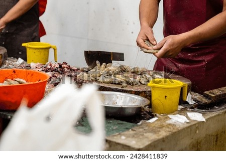 A close-up view of skilled hands cleaning fresh prawns at a vibrant seafood stall