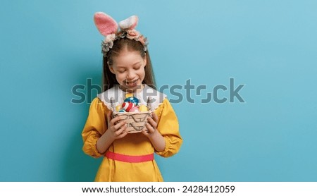 Cute little child wearing bunny ears on Easter day. Girl with painted eggs. Royalty-Free Stock Photo #2428412059