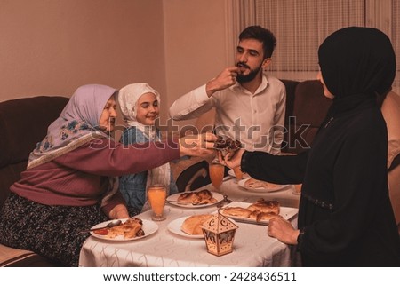 Happy Muslim family having iftar dinner during Ramadan dining table at home. High quality photo