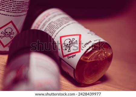 Vaping juice plastic bottles with a danger skull warning sign on the label, close-up shot.