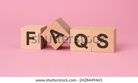 wooden blocks displaying FAQS arranged on a pink surface, suggests a focus on implies providing clarity, assistance, and guidance on common queries or concerns