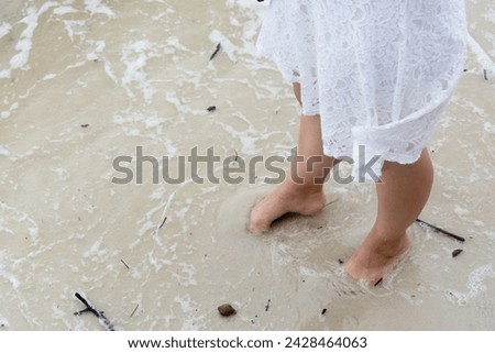 Half body of an unidentified person wet their feet in the beach sand. Relaxation concept. Royalty-Free Stock Photo #2428464063