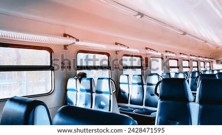 Aisle inside passenger car of suburb train with comfortable blue seats and windows. Traveling by railway. Railroad trip. Background with train indoors. Soft focus. film grain pixel texture. Defocused.