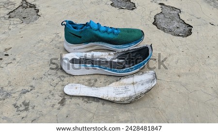 You can see blue carbon plate running shoes with white midsoles that have been split so they are separated on the floor.  The carbon plate in the middle of the midsole looks broken.
